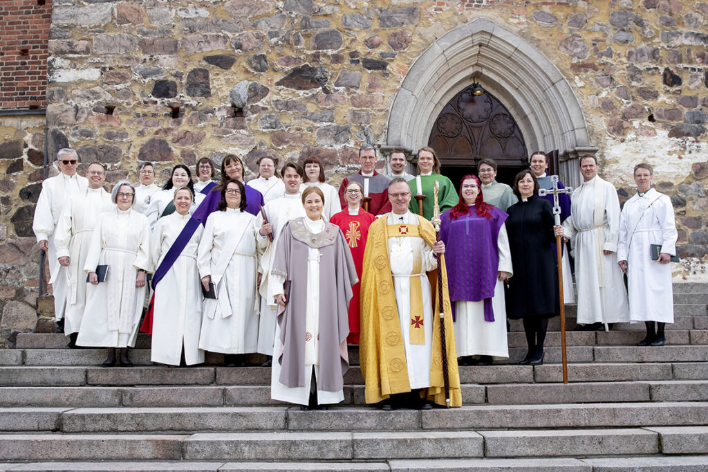 Pappeja ja diakoniantyöntekijöitä seisomassa Turun tuomiokirkon portailla messun jälkeen.