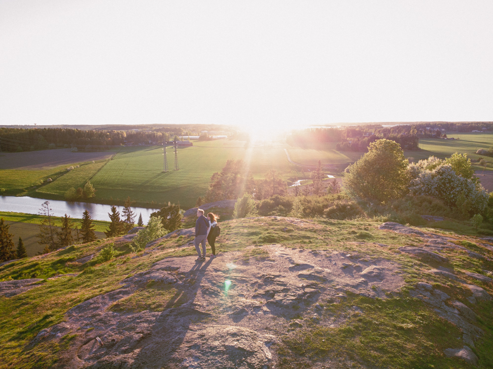 Kaksi ihmistä seisoo ilta-auringossa kalliolla